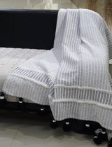 Hand loom Woven Textured Throw with Off White and Black Stripes and Black Tassels draped on a chair