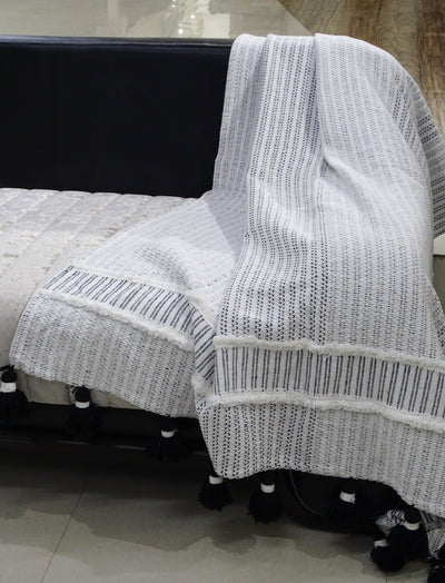 Hand loom Woven Textured Throw with Off White and Black Stripes and Black Tassels draped on a chair