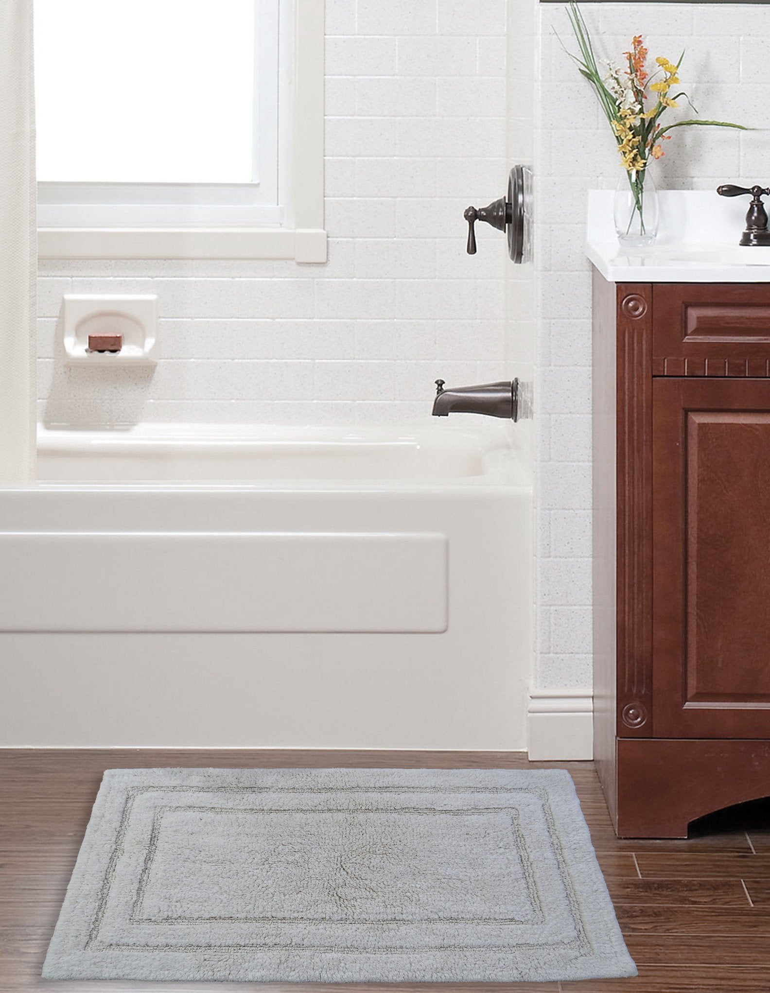 Ivory Color Plain Bath Rug by CHICOS HOME, showing simple border on bathroom floor
