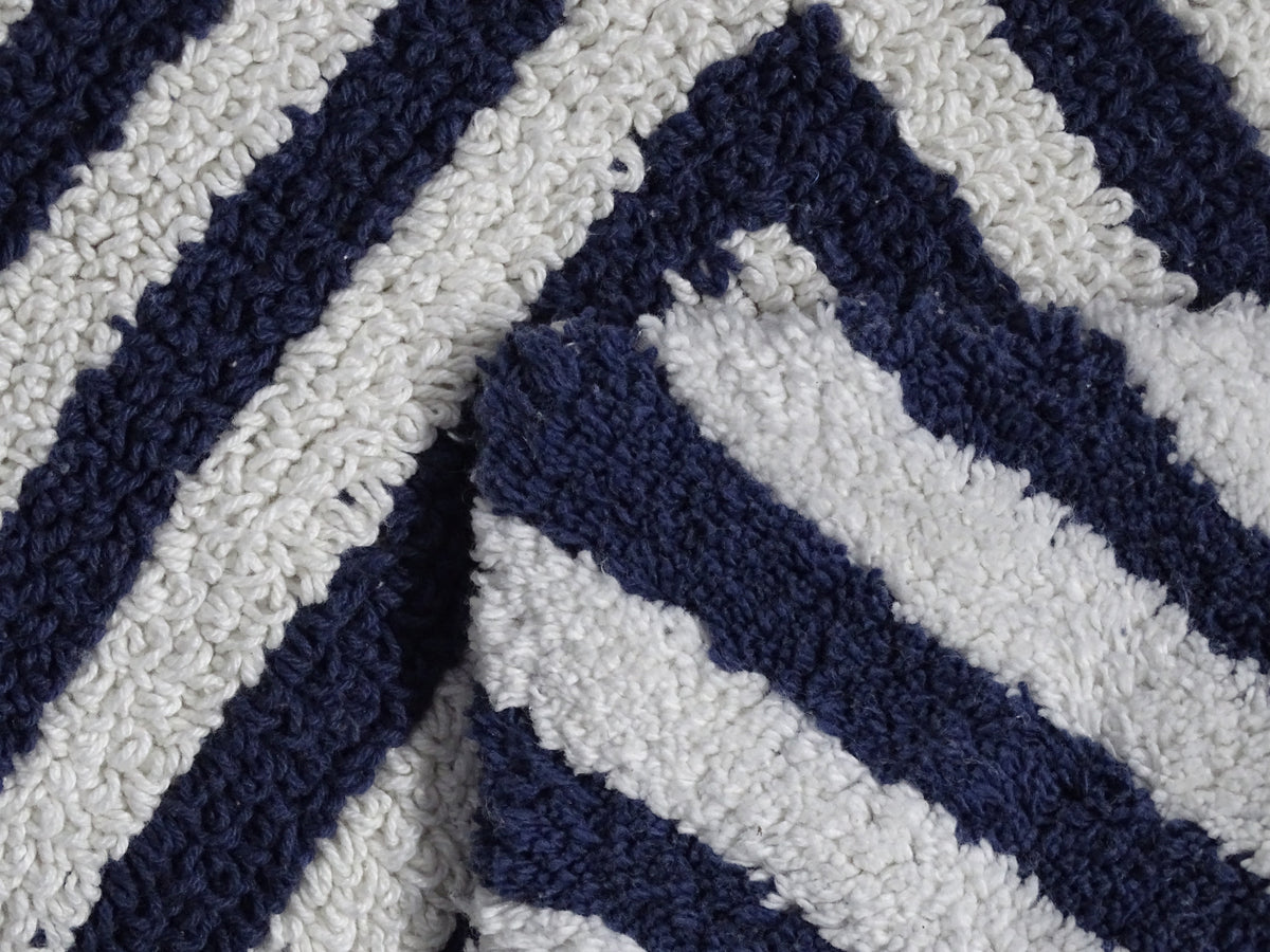 Close-up of a looped bath rug showing a charcoal and ivory chevron pattern with alternating diagonal stripes of textured fabric.