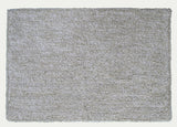 Ivory and white geometric patterned bath rug by CHICOS HOME on bathroom floor