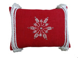 Rectangular red throw pillow with white embroidered snowflake centered, featuring braided white tassels on all four corners against a white background.
