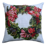 Square pillow with a painted Christmas wreath featuring red poinsettias, pinecones, and green foliage on a light background.
