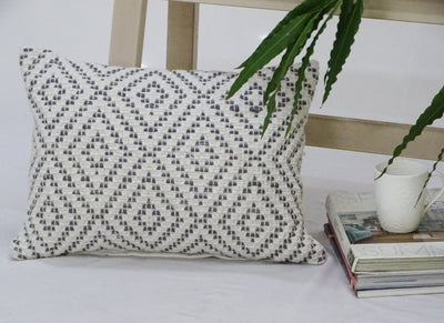 Decorative cotton throw pillow with diamond pattern texture resting on a chair