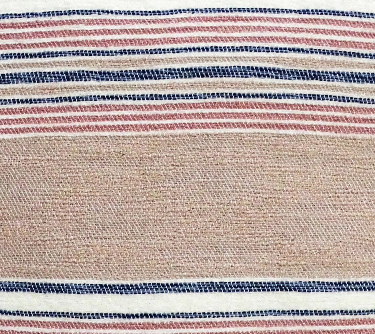 Close-up of a throw pillow fabric showing textured beige center with horizontal navy blue, red, and white stripes above and below.