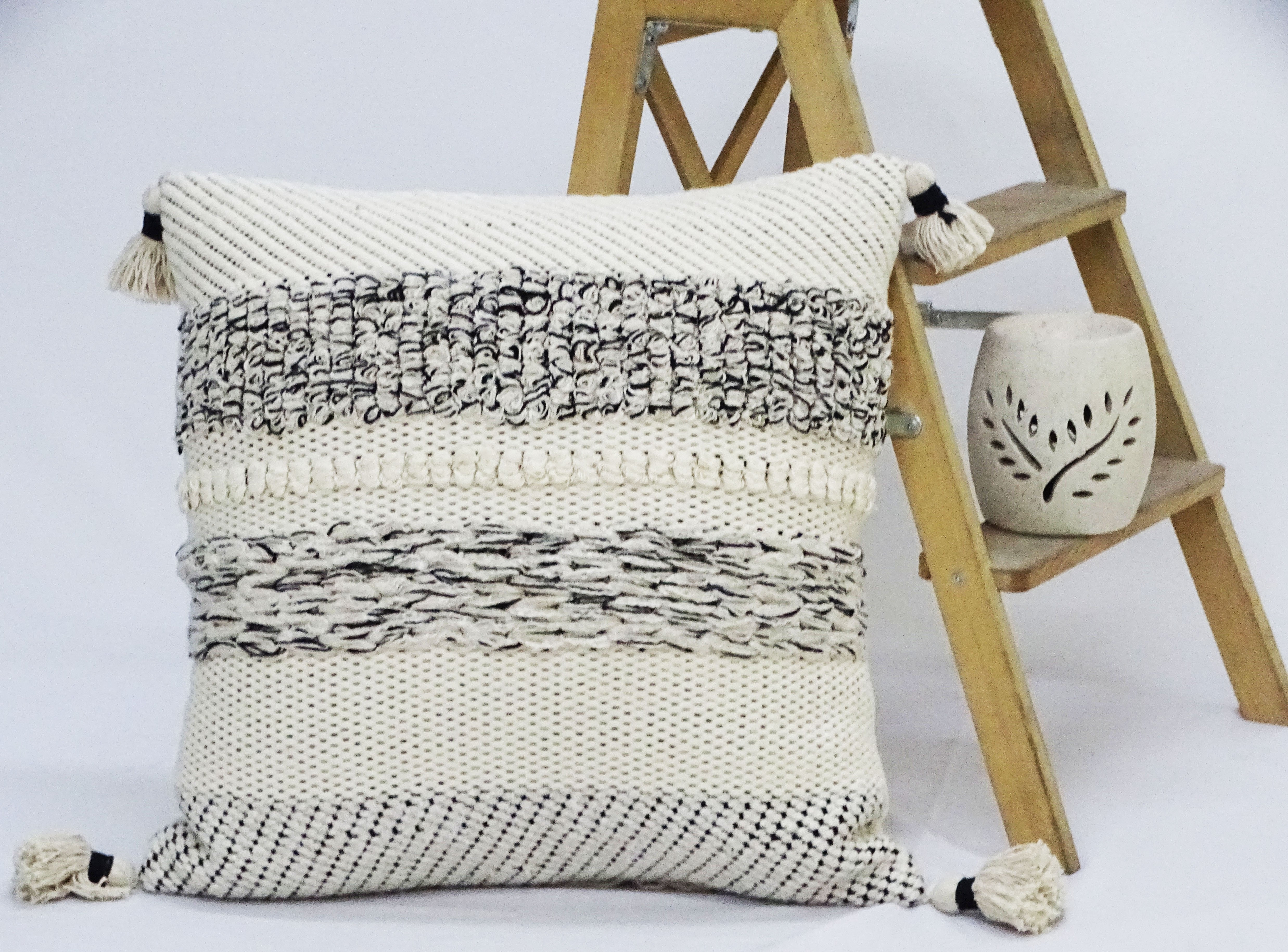 Black and beige striped 22x22 inch throw pillow with corner tassels on a neutral couch