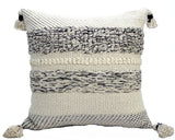 Square throw pillow with cream base and black woven textured stripes, featuring tassels on all four corners, shown front-facing on white background.
