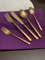 Vibhsa shiny gold 5 piece flatware set arranged on white material