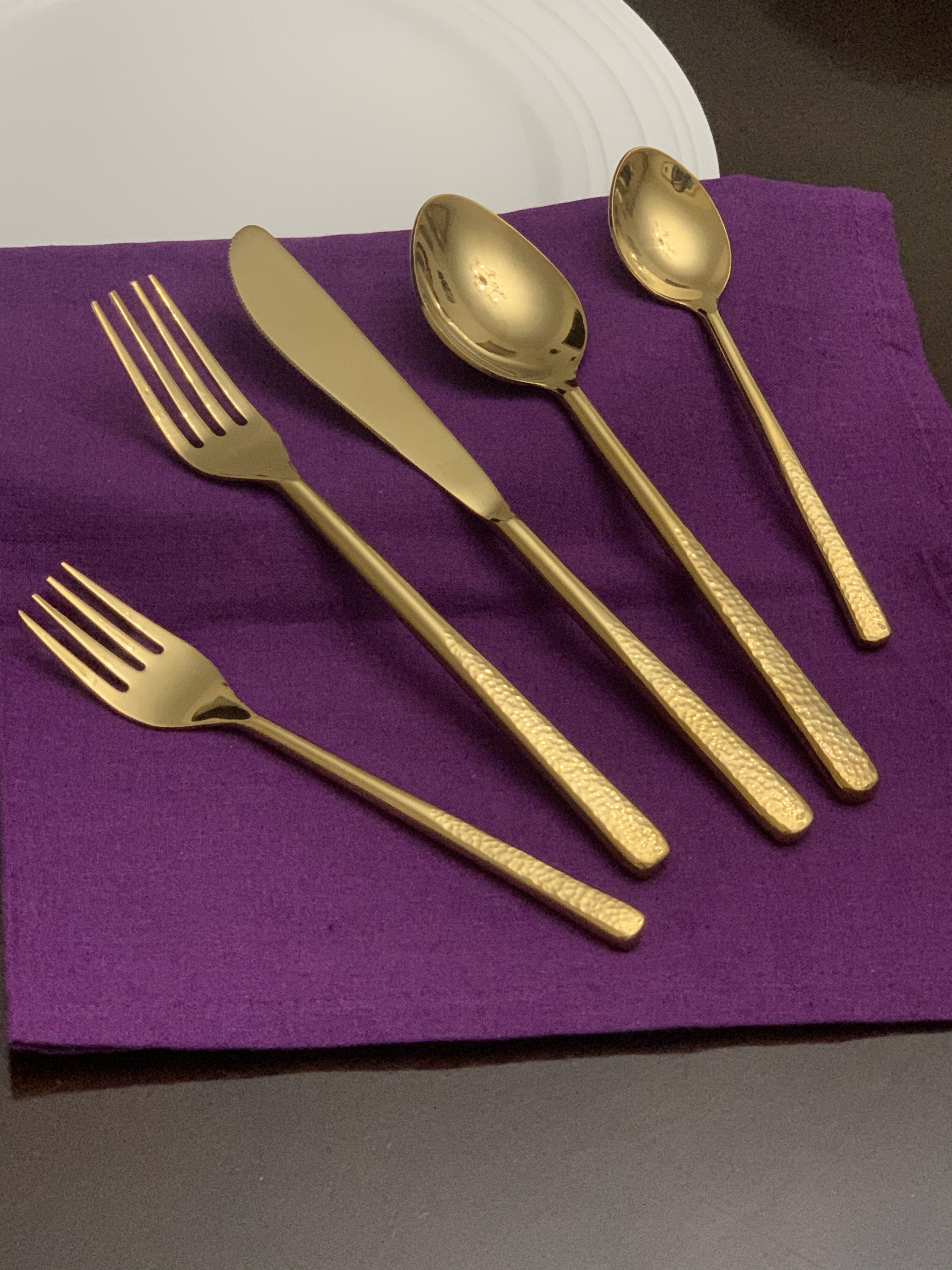 Vibhsa shiny gold 5 piece flatware set arranged on white material