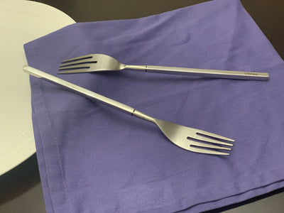 Set of six polished stainless steel dinner forks laid out on a wooden surface