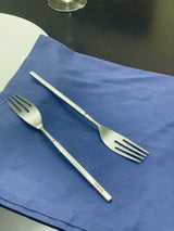Set of six Vibhsa polished stainless steel salad forks displayed on textured gray fabric