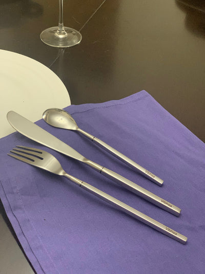 Vibhsa 18-piece stainless steel flatware set with dinner forks, dinner knives, and dessert spoons arranged on white surface
