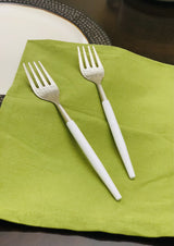 Set of six Vibhsa stainless steel dinner forks with hammered mouth and white handles arranged on a beige cloth