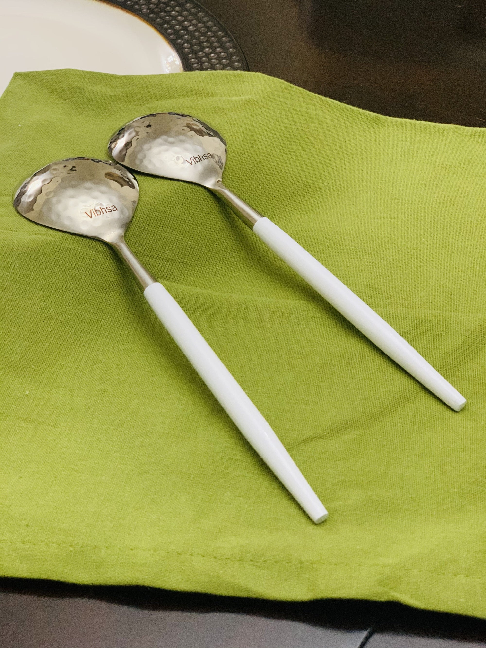 Vibhsa 6-PC Tablespoon Serving set with hammered mouth and white handles arranged on white plate.