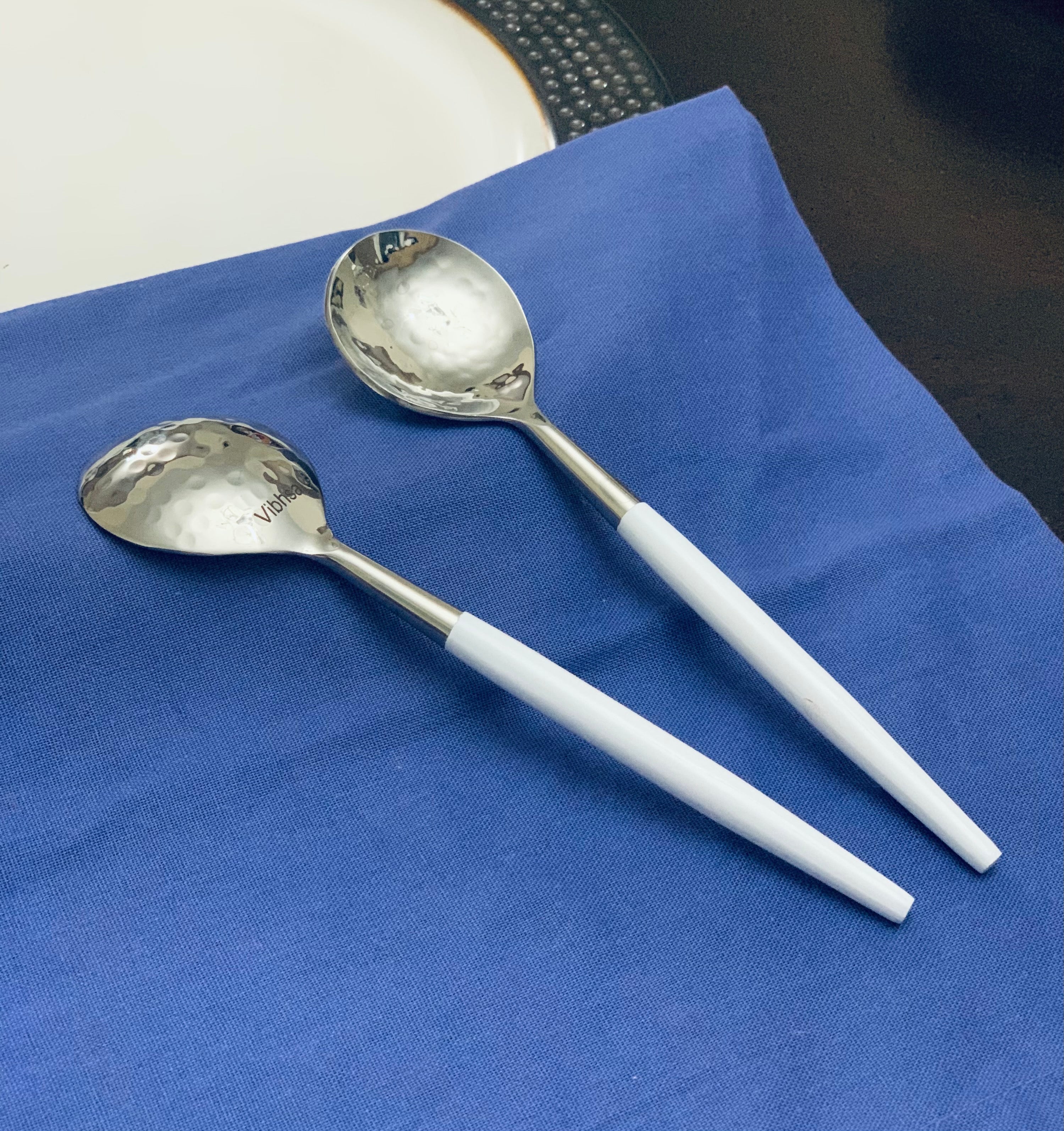 6-PC Stainless Steel Soup Spoon set with hammered mouth and white handles arranged on a linen cloth