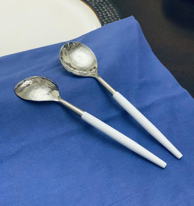 6-PC Stainless Steel Soup Spoon set with hammered mouth and white handles arranged on a linen cloth