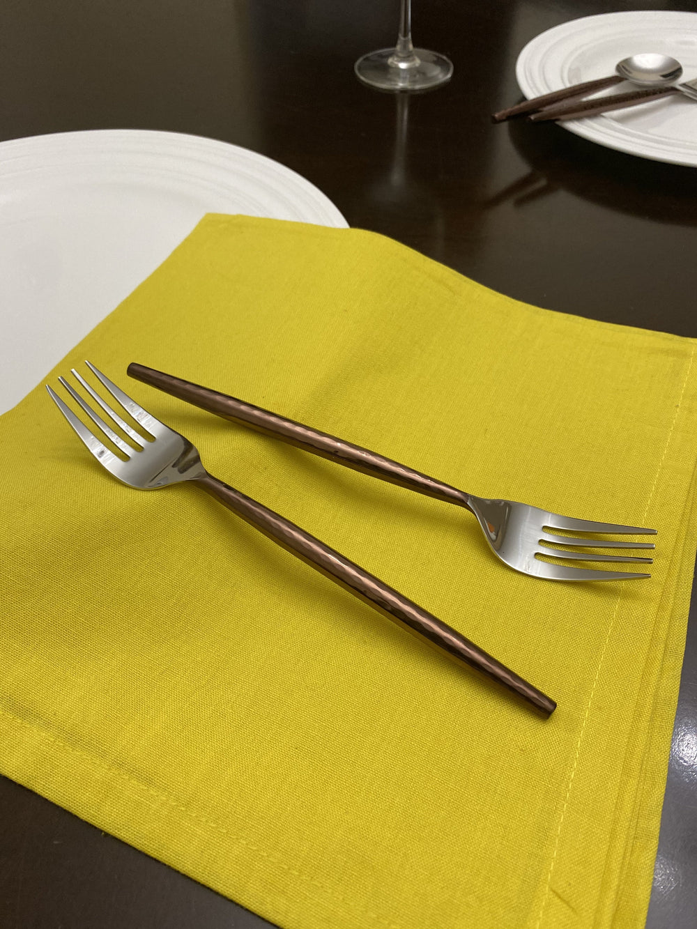 Set of six Vibhsa brown stainless steel dinner forks with hammered handles on a dark surface