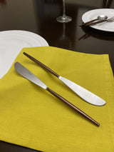 Set of six stainless steel dinner knives with hammered brown handles and polished blades displayed on a textured surface