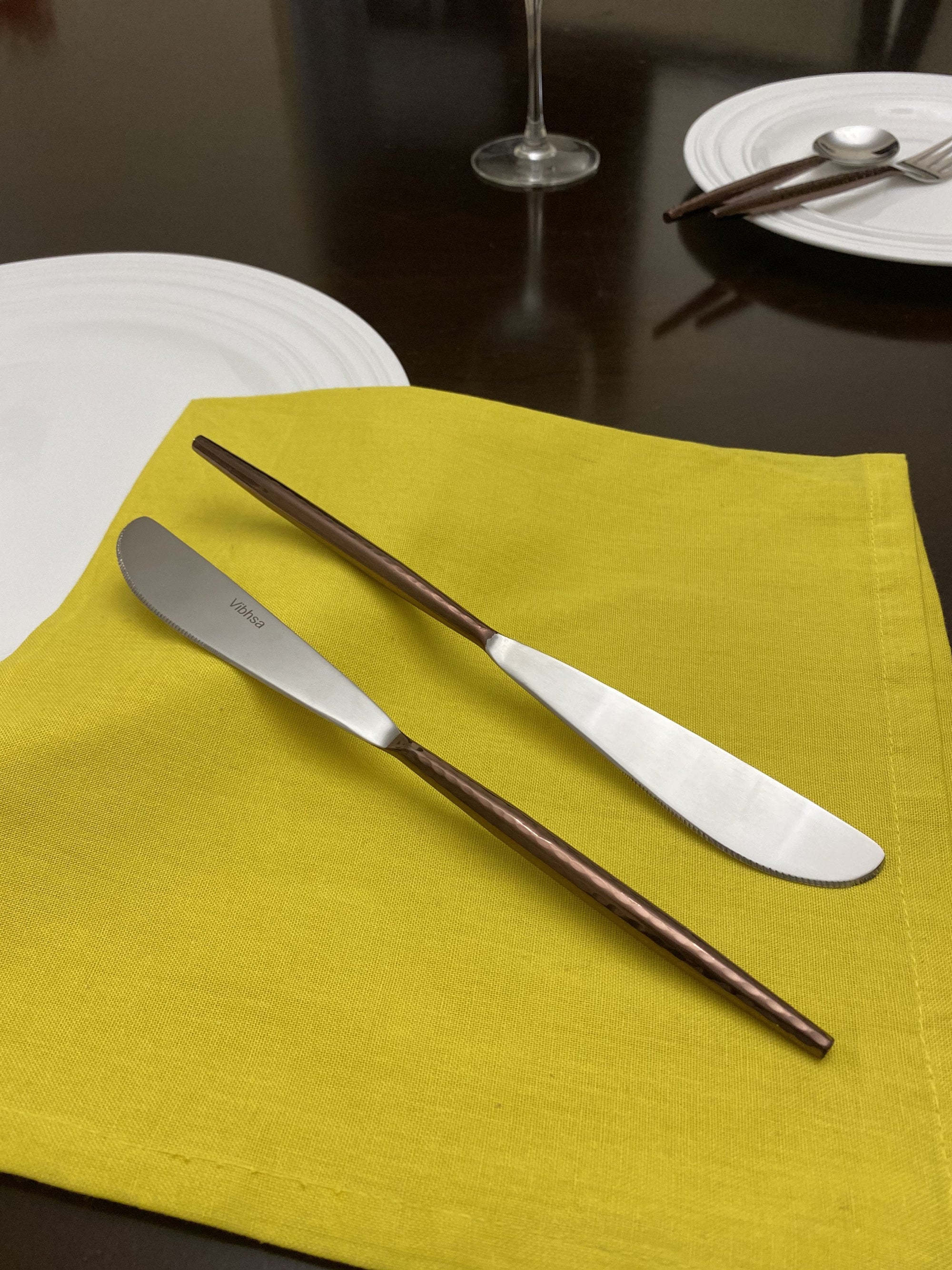 Set of six stainless steel dinner knives with hammered brown handles and polished blades displayed on a textured surface