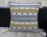 Designer Striped Pillow with mini pom-poms and tassels displayed on dark chair
