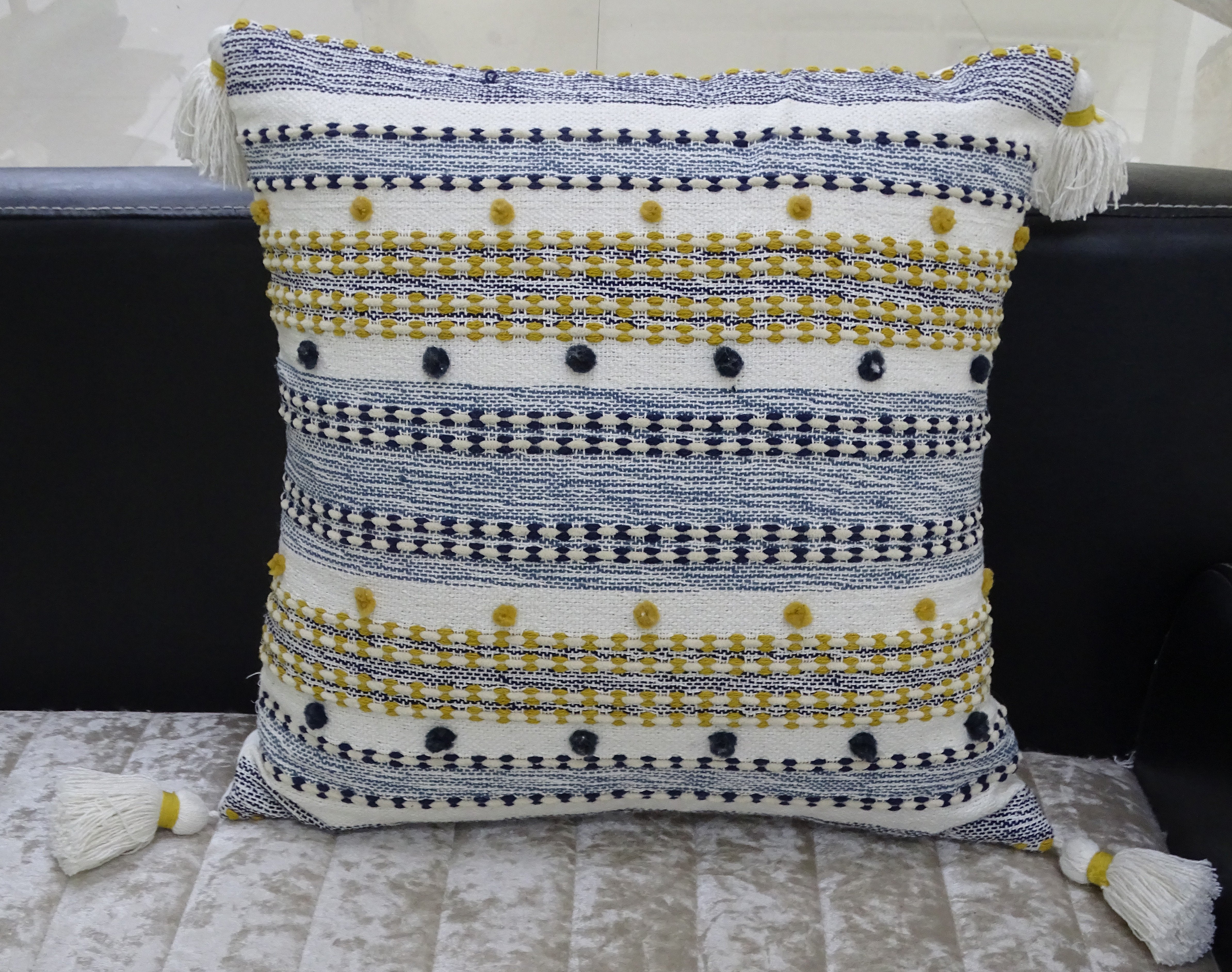 Designer Striped Pillow with mini pom-poms and tassels displayed on dark chair