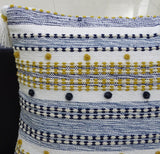 Rectangular pillow with alternating navy blue and mustard yellow striped patterns, featuring small pom details and a white tassel on one corner.