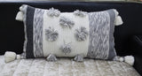 Melange striped throw pillow with large pom-poms and tassels on a sofa