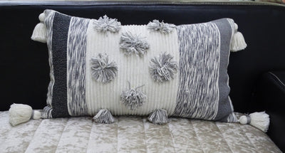 Melange striped throw pillow with large pom-poms and tassels on a sofa