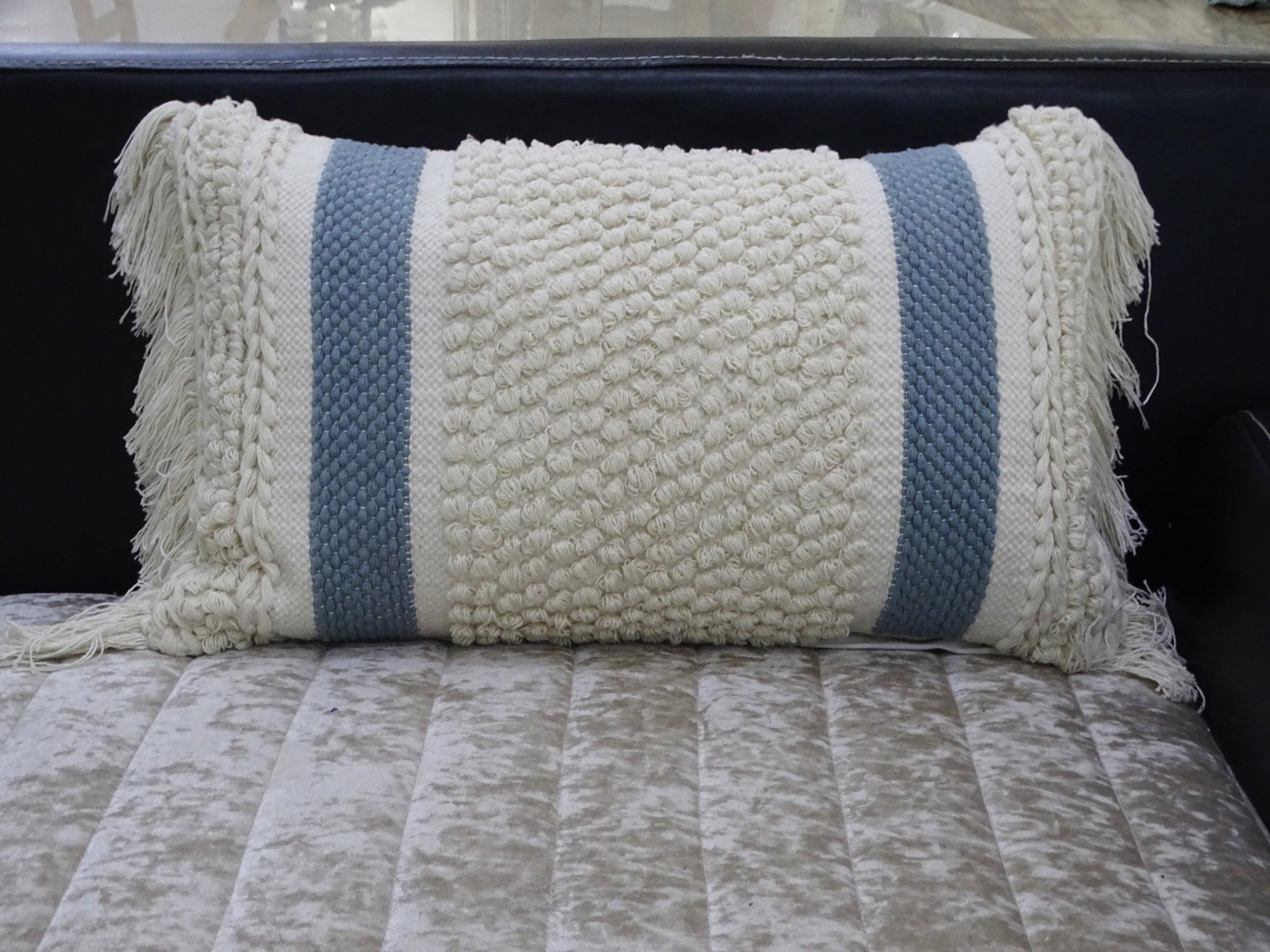Handwoven striped decorative pillow with loop texture and fringes displayed on a wooden chair