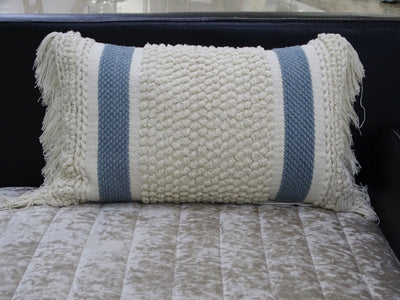 Handwoven striped decorative pillow with loop texture and fringes displayed on a wooden chair
