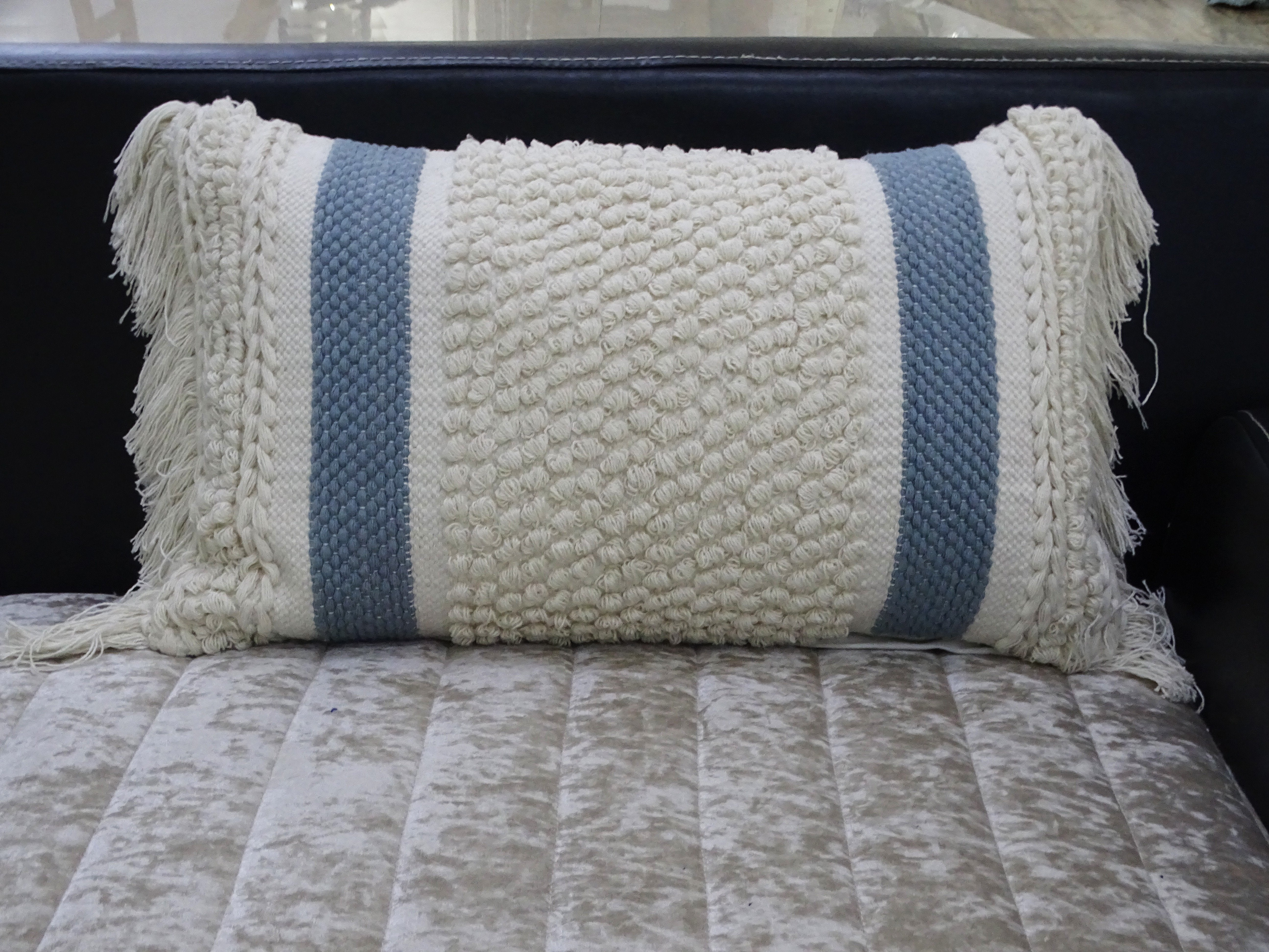 Handwoven striped decorative pillow with loop texture and fringes displayed on a wooden chair