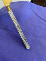 Flatware piece with a gold-colored top and a textured silver handle featuring a repeating hexagonal pattern, resting on a purple fabric background.