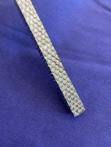 Close-up of a metallic rectangular bar with a hexagonal textured pattern on a purple fabric background.