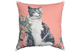 Square pink decorative pillow with a black and white cat illustration surrounded by pink flowers and green leaves, featuring white pom-poms at each corner.