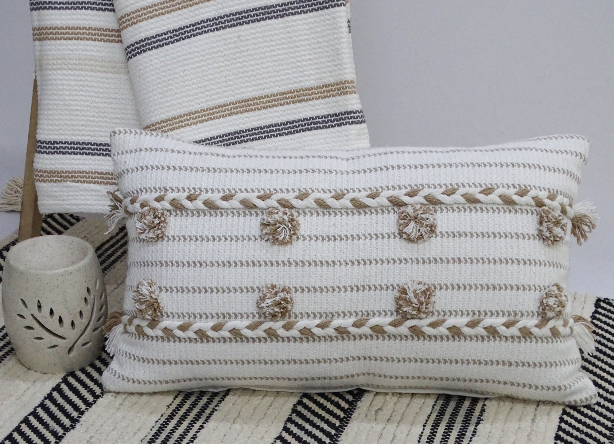 Handwoven 14" x 24" throw pillow in bright colors with braided textures and pom-poms on the edges