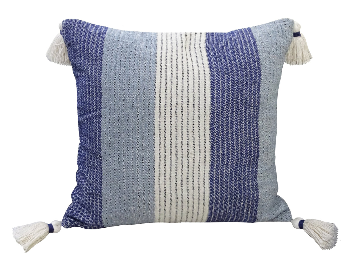 Square handwoven throw pillow with vertical stripes in shades of blue and white, featuring white tassels on each corner.