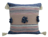 Square throw pillow with horizontal blue, beige, and pink stripes, featuring navy and light blue pom-poms in the center and off-white tassels at each corner.