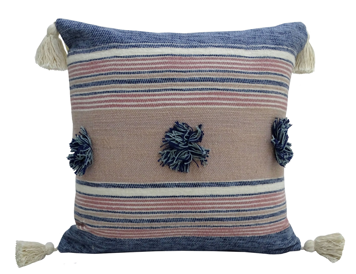 Square throw pillow with horizontal blue, beige, and pink stripes, featuring navy and light blue pom-poms in the center and off-white tassels at each corner.