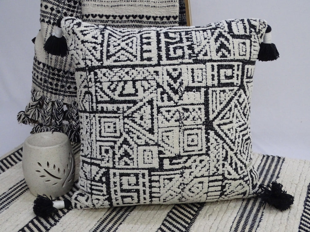 Colorful 20 by 20 inch throw pillow with corner tassels on a neutral surface