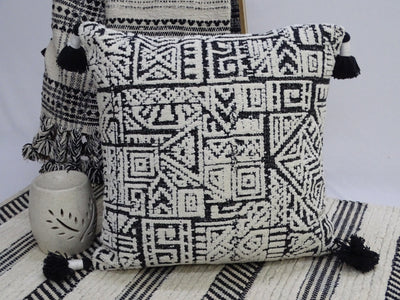 Colorful 20 by 20 inch throw pillow with corner tassels on a neutral surface
