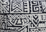 Close-up of a black and white textile with a geometric, tribal-inspired pattern composed of squares and angular lines.