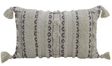 Rectangular handwoven throw pillow with cream background, dark brown geometric stripes, textured patterns, and tassels at each corner