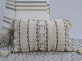 Handwoven rectangular throw pillow with fringed corners on a neutral couch
