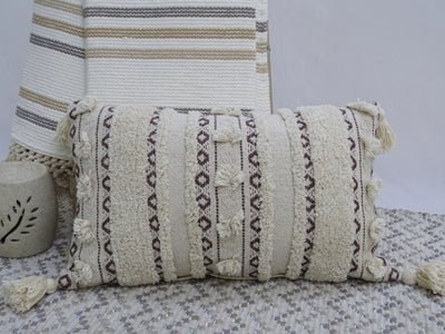 Handwoven rectangular throw pillow with fringed corners on a neutral couch