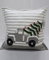 Square decorative pillow with light gray and white horizontal stripes, featuring a textured gray truck carrying a green Christmas tree with red ornaments and silver tinsel on the back.