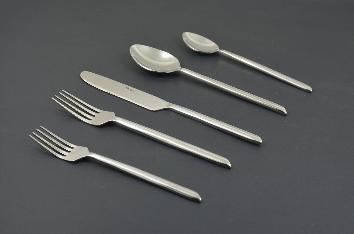 Five-piece stainless steel flatware set including two spoons, a knife, and two forks with sleek, slightly tapered handles on a dark gray background.