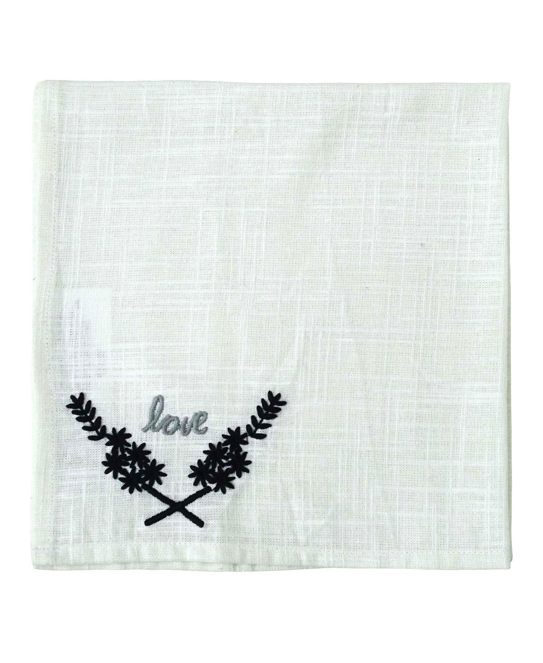 Four square white cloth napkins folded and stacked, featuring black 'Love' embroidery at the corner