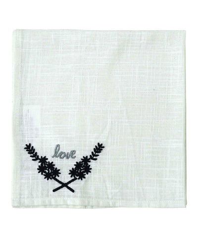 Four square white cloth napkins folded and stacked, featuring black 'Love' embroidery at the corner