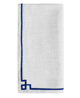 Set of four cotton table cloth napkins with blue embroidered edges neatly arranged on a wooden surface.