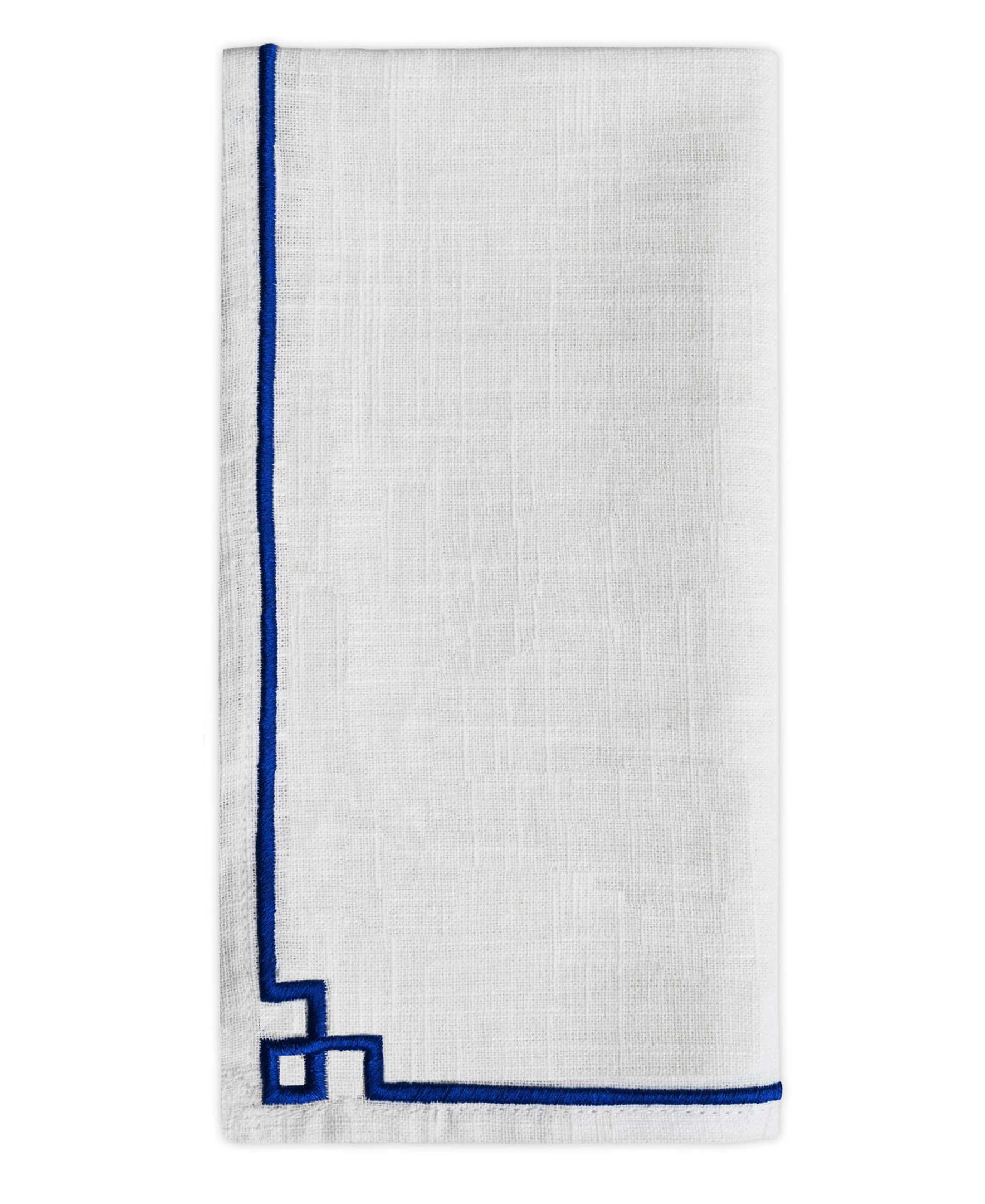 Set of four cotton table cloth napkins with blue embroidered edges neatly arranged on a wooden surface.